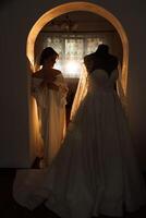 une magnifique brunette la mariée avec une tiare dans sa cheveux est avoir prêt pour le mariage dans une magnifique peignoir dans boudoir style. fermer mariage portrait, photo. photo