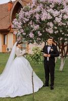 mariage. l'amour et couple dans jardin pour mariage. célébrer le la cérémonie et engagement. enregistrer le date. confiance. le la mariée et jeune marié sont permanent contre le Contexte de épanouissement printemps des arbres. photo