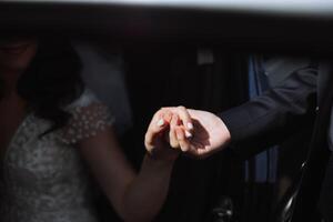une magnifique mariée, séance dans une voiture, donne sa main à sa mari. une magnifique la mariée avec une bouquet de fleurs dans sa mains est séance dans une élégant coûteux auto. photo