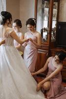 copains réjouir avec le la mariée dans le Matin. elles ou ils prendre des photos, sourire, Aidez-moi le la mariée boucler sa robe. photo