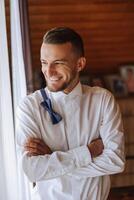 une élégant portrait de le jeune marié en train de préparer pour le mariage la cérémonie dans le Matin. du marié Matin. préparation pour le du marié Matin. le jeune marié met sur une veste. le sur de soi Regardez de une mature homme. photo