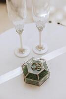 or mariage anneaux sur vert forêt mousse dans une verre boîte. le concept de un événement agences pour le la cérémonie de le la mariée et jeune marié. photo