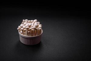 petit blanc comestible hêtre champignons avec sel et épices sur une plaine Contexte photo