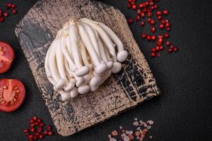 petit blanc comestible hêtre champignons avec sel et épices sur une plaine Contexte photo