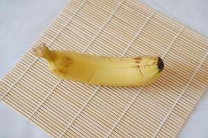 mûr banane sur une bambou serviette de table sur une blanc Contexte. photo