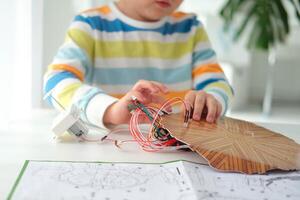 peu garçon performant ou en train d'étudier science avec fils, Connexions. électronique expérience. le enfant est expérimenter à maison. photo