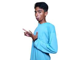 excité asiatique homme portant bleu T-shirt montrer du doigt à le copie espace sur le côté, isolé blanc Contexte. photo