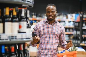 africain américain homme dans épicerie boutique achat du vin photo