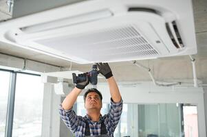 concentré Jeune Indien ingénieur réglage en haut air Conditionneur. photo