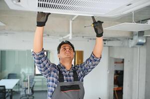 concentré Jeune Indien ingénieur réglage en haut air Conditionneur. photo