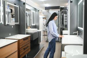 Jeune femme choisir Nouveau salle de bains meubles à le plomberie magasin avec beaucoup de sanitaire des biens photo