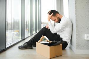 mis à la porte frustré homme dans costume séance sur sol dans Bureau photo