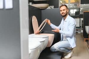 dans une plomberie magasin, une homme choisit une Nouveau toilette bol photo