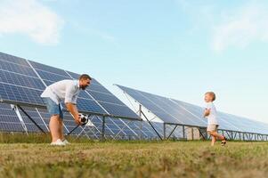 une père et le sien peu fils jouer Football près le solaire panneaux. le concept de renouvelable énergie. photo