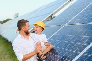 homme montrant peu enfant le solaire panneaux pendant ensoleillé journée. père en présentant à le sien enfant moderne énergie Ressource. peu pas à alternative énergie. photo