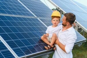 homme montrant peu enfant le solaire panneaux pendant ensoleillé journée. père en présentant à le sien enfant moderne énergie Ressource. peu pas à alternative énergie. photo