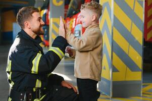 sapeur pompier en portant enfant garçon à enregistrer lui dans Feu et fumée, pompiers porter secours le garçons de Feu photo