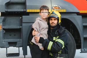 sapeur pompier en portant enfant garçon à enregistrer lui dans Feu et fumée, pompiers porter secours le garçons de Feu photo