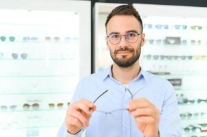soins de santé, vue et vision concept. content homme choisir des lunettes à optique magasin, sélectif concentrer photo