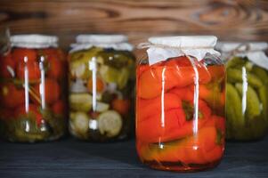 en conserve concombres et tomates avec artisanat couvercles sur une en bois Contexte. concombres et tomates avec endroit pour texte. les stocks de en conserve aliments. récolte, les stocks pour le l'hiver. photo