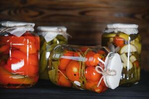 verre pots avec mariné concombres cornichons, mariné tomates et chou. pots de divers mariné des légumes. en conserve nourriture dans une rustique composition. photo