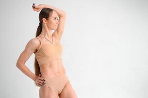 image de une pompé en haut abdos. magnifique sportif femme posant dans studio sur une blanc Contexte. aptitude, la musculation, aérobie concept. photo