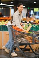 Jeune femme achat des légumes à épicerie marché photo