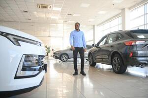 Jeune Afro-américain homme venu à voir automobiles dans concession ou voitures salle d'exposition photo