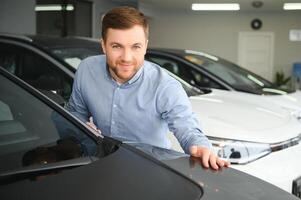 une Jeune homme choisit une Nouveau voiture à une voiture concession. photo