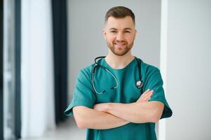 portrait de souriant médecin à la recherche à caméra avec bras franchi dans médical Bureau photo