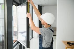 Beau Jeune homme installation baie fenêtre dans Nouveau maison construction site photo