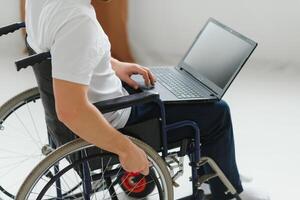 portrait de souriant la personne avec une invalidité séance dans fauteuil roulant et travail sur portable de maison. pigiste concept. photo