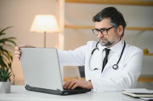 portrait de Sénior médecin dans blanc manteau à lieu de travail. photo