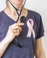 coup de le femelle médecin contre le blanc mur avec rose ruban, comme une symbole de une Sein cancer conscience. concept photo