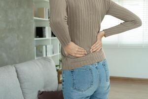 femme en portant sa inférieur retour tandis que et souffrir de insupportable douleur santé et problèmes, chronique retour douleur, mal au dos dans Bureau syndrome, scoliose, hernie disque, muscle inflammation photo