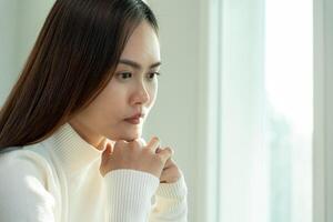 malheureuse femme asiatique fille déçue, triste à cause d'un problème à la maison seule, se sentir seule, stressée, souffrant d'une mauvaise relation, rompre, divorcer, femme confuse, dépression santé mentale, solitude photo