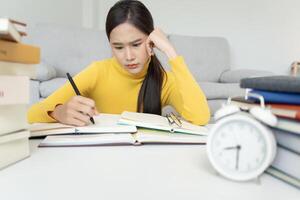 une étudiante asiatique a de l'anxiété à cause des examens, les femmes se préparent aux tests et apprennent les leçons à la bibliothèque. stress, désespoir, hâte, incompréhension lecture, découragement, attente, connaissance photo