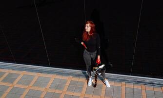 une femme permanent sur une trottoir en portant une planche à roulette. une femme permanent sur une trottoir en portant une planche à roulette photo