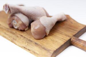 brut non cuit poulet jambes, pilons sur en bois planche photo