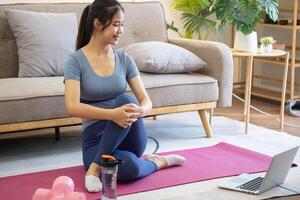 femmes sont élongation, à maison, et aptitude femmes exercice ou faire yoga dans leur chambre pour santé et bien-être une en bonne santé, calme femelle la personne formation ou travail sur le maison sol. photo