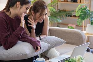 détendu Jeune asiatique femme profiter relaxation sur une confortable canapé à maison. le magnifique fille calmement se détend et respire Frais air dans le maison. regarder films et social réseaux. photo