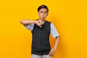 jeune homme asiatique à la recherche de mécontentement et de colère montrant le rejet avec le geste du pouce vers le bas photo