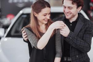 maintenant son rêve devient réalité. vendeur de voitures donnant la clé de la nouvelle voiture aux jeunes propriétaires attrayants photo