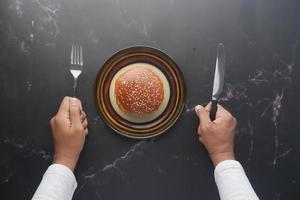 homme affamé en attente de manger un hamburger de boeuf sur la table en gros plan photo