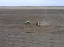 semis de maïs. tracteur avec une semoir sur le champ. en utilisant une semoir pour plantation maïs. photo