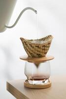 verser chaud l'eau dans le sol café dans une goutteur fabriqué de bambou tisser. photo