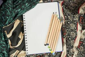 une carnet de notes, des crayons et une écharpe sur une table photo