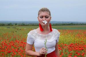 blanc coquelicot fleur dans le mains de une fille dans le milieu de une champ de rouge coquelicots photo