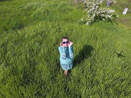 Jeune fille dans une lumière vert robe sur le pelouse avec vert herbe. photo