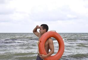 le homme sur le plage avec une bouée de sauvetage photo